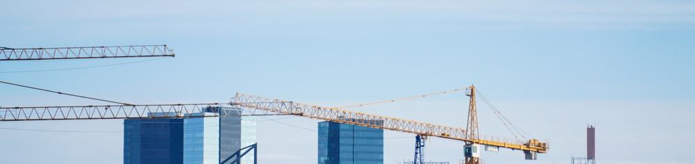 A city skyline under construction, tower cranes against a clear sky