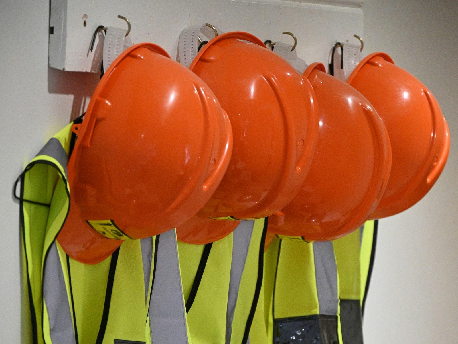 Orange hard hats and high-visibility safety vests hanging ready for a work crew